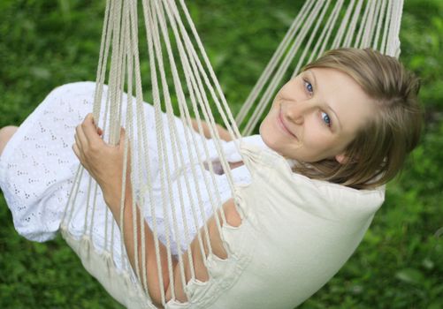 Young happy woman relaxing and swinging in hammock. Soft focus.