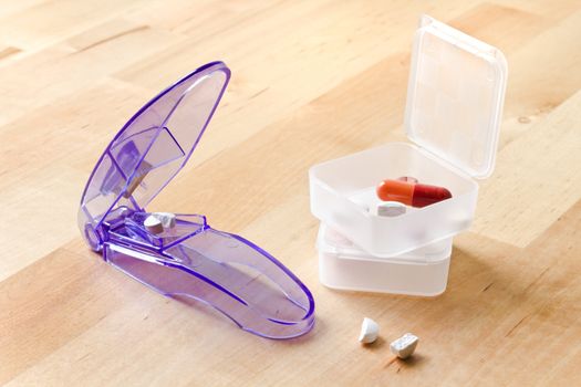 Pillboxes and pills cutted by pill cutter on wooden table