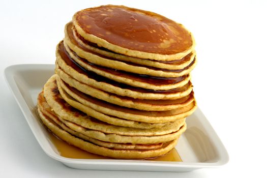 Stack of homemade pancakes with syrup on a white plate. Isolated on white