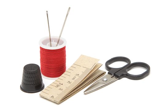 Sewing tools: spool of thread, needles, scissors, measuring tape, thimble isolated on white background