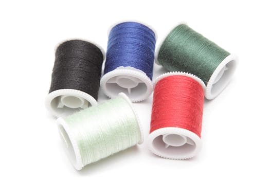 Group of spools of thread of various colors isolated on white background
