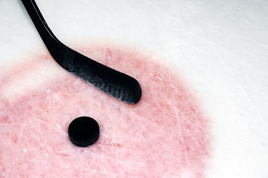 Hockey sport background: graphite stick and puck on real arena used and scratched ice.