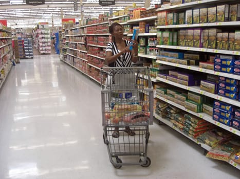 A woman is paying special attention and checking the labels of the items she is shopping in the supermarket