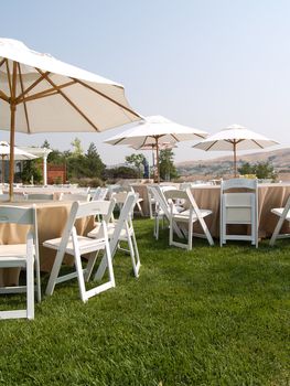 Tables,  chairs, and umbrellas arranged and ready for an outdoor party.