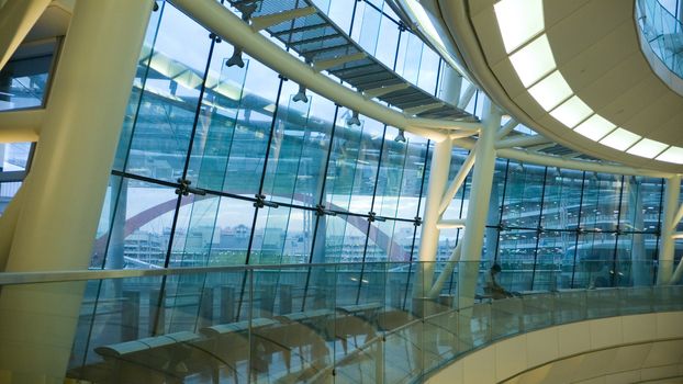 futuristic atrium environment, glass wall and metallic construction inside big public hall with sitting man