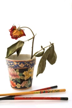 Chopsticks and vase with wilted rose isolated on white