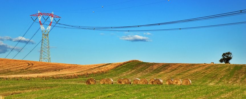 Italian landscape with power pylon and hay bales