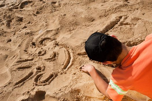 Creative teenager sketching a cartoon on beach sand