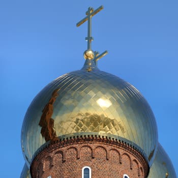 Golden dome of the Orthodox church with blue sky background in Russia.