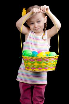 A cute girl holding up her colorful easter basket.