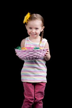 A happy toddler looks excited to show the viewer her basket full of eggs.