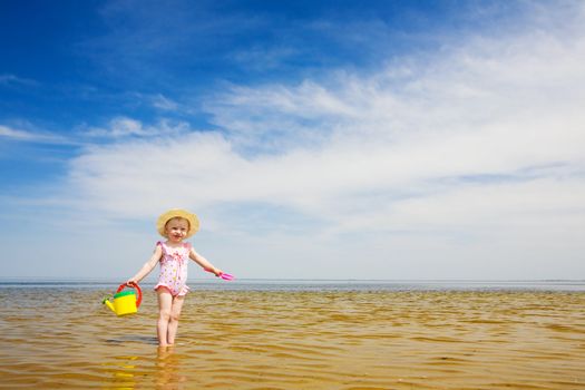 small girl with watering-pot on the seashore