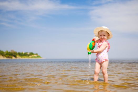 small girl with watering-pot on the seashore