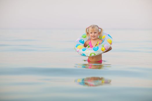 small girl in water with inflatable buoy