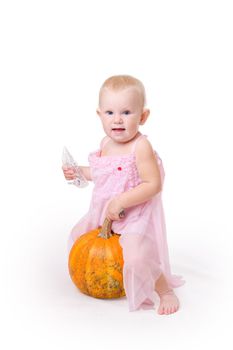 smiling little girl embraces pumpkin and a crystal shoe near by