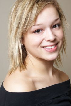 A head and shoulders portrait of a happy young woman who is smiling.