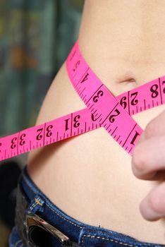 A woman measures her waistline to account for her ideal size and fitness.