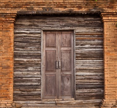 Old solid wood door and wall with bricks line.