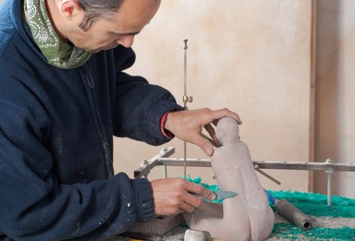 Sculptor patiently working on a small marble statue