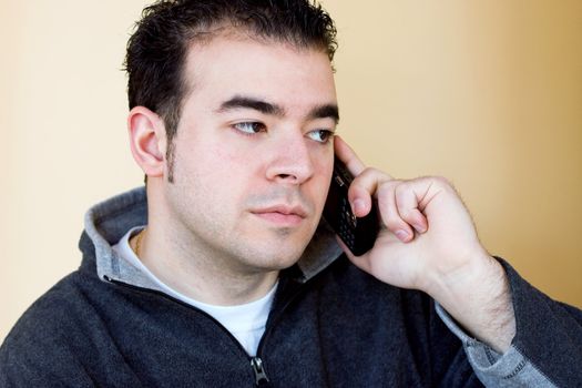 A young man talking on his cell phone.  He is holding the phone with his right hand but listening with his left ear.