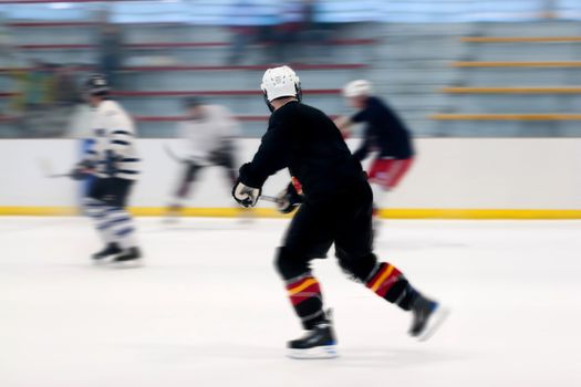 Panned motion blur of two hockey players skating down the ice rink.