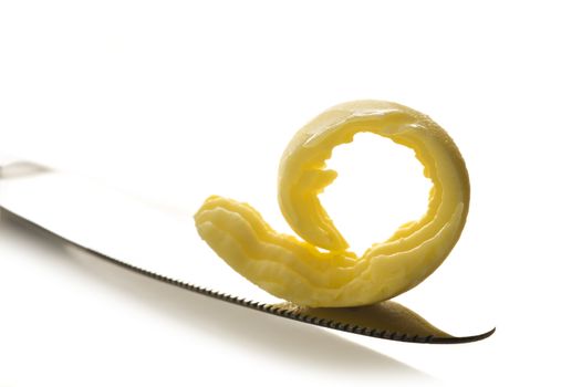 Curl of butter on knife tip on white background