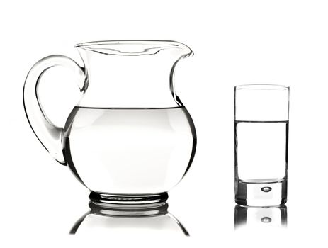 Glass and glass pitcher on white background with space for text