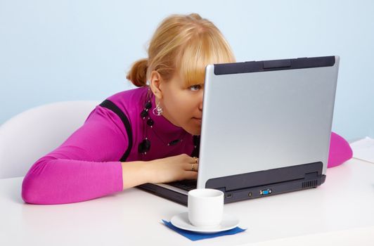 A beautiful young girl - is looking closely at the laptop monitor