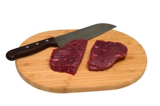 Piece of beef and a knife on a wooden cutting board.