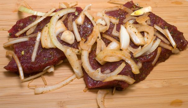 Marinated beef with onions on a cutting board.