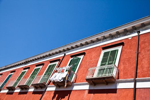 Detail of an ancient red house with a blue sky background in Procida Isle, Italy