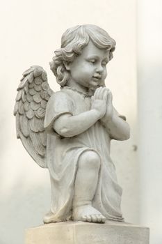 Cute winged Angel statue in praying pose with side view