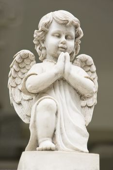 Cute winged Angel statue in praying pose in low angle view