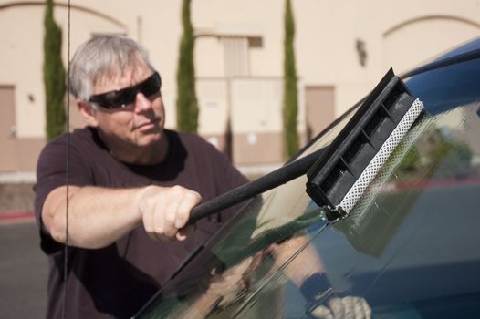 man cleaning windshield of his car 