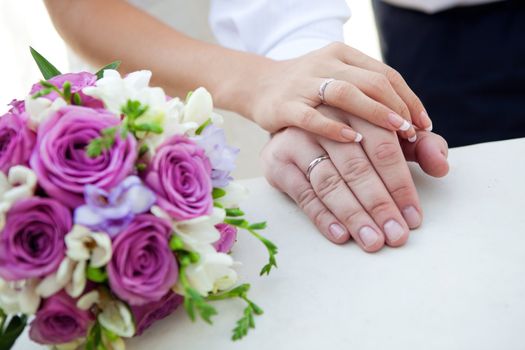 hands of bride and groom with bouquet