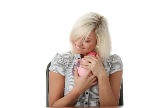 Young blond woman with her piggy bank, isolated on white background