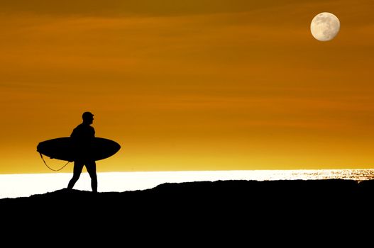 Surfer walking as the moon rises and the sun sets towards the pacific ocean along the cliffs in Santa Cruz to get that last ride