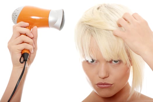 Young blonde woman using hair drier