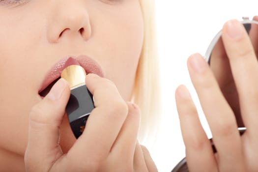 A beautiful young woman applying her make-up in the mirror