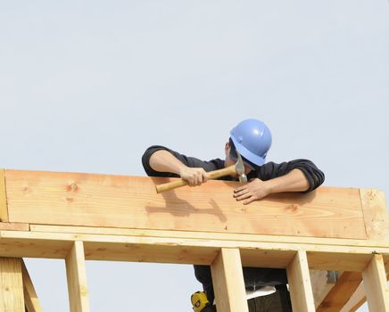Carpenter hammering in nail on a commercial construction site