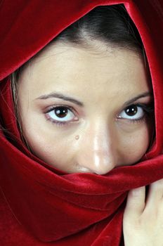 Beautiful young brunette woman with red velvet shawl over head in closeup