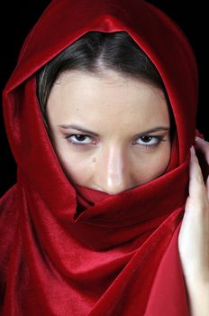Beautiful young brunette woman in closeup with red shawl over face