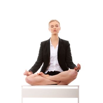 Beautiful blond businesswoman sitting on white desk in lotus flower position of yoga. Isolated on white