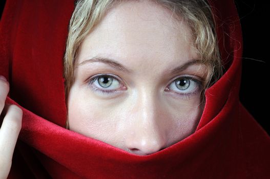 Beautiful young blond woman in closeup with shawl over her face