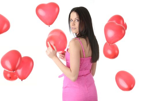 Beautiful young woman in pink elegant dress with red heart shaped balloon on a white background (love and valentines concept)