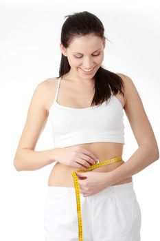 Sexy, fit, young woman measuring her waist, over white background