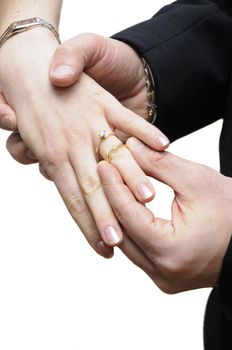 Groom placing ring on finger of bride at wedding isolated over white