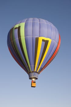 colorful balloon rising at dawn in the cold air at the Taos hot air balloon festival