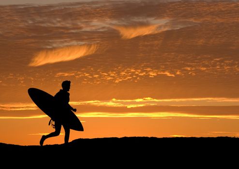 Surfer running out to sea to get the last wave in before sunset