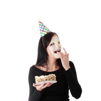 Funny portrait of beautiful young caucasian woman with birthday cake on her face, isolated on white background